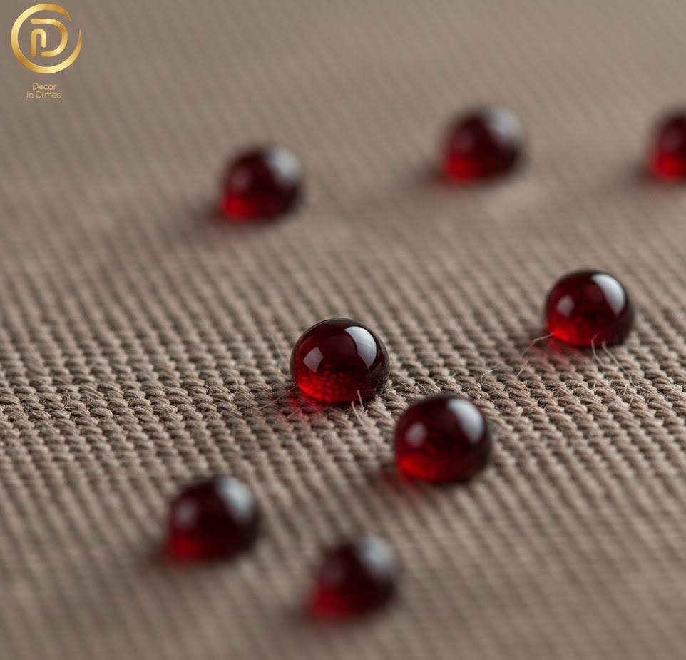 Close-up of red liquid beading on the surface of Crypton performance fabric, featuring the Decor in Dimes logo.